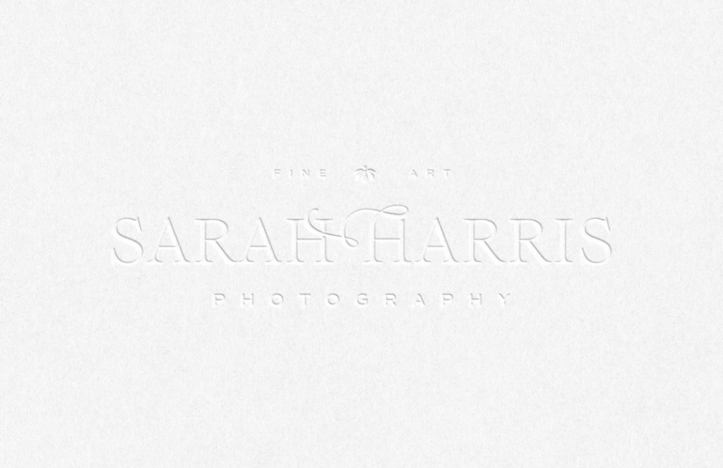 A letter-pressed mockup of a classic feminine logo design, using a serif font with custom flourishes.